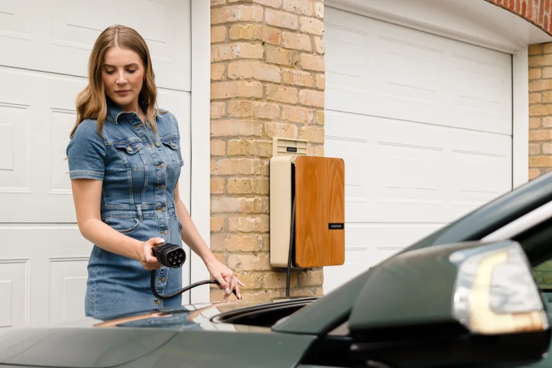 Bewoner laadt haar elektrische auto aan een laadpaal bij huis